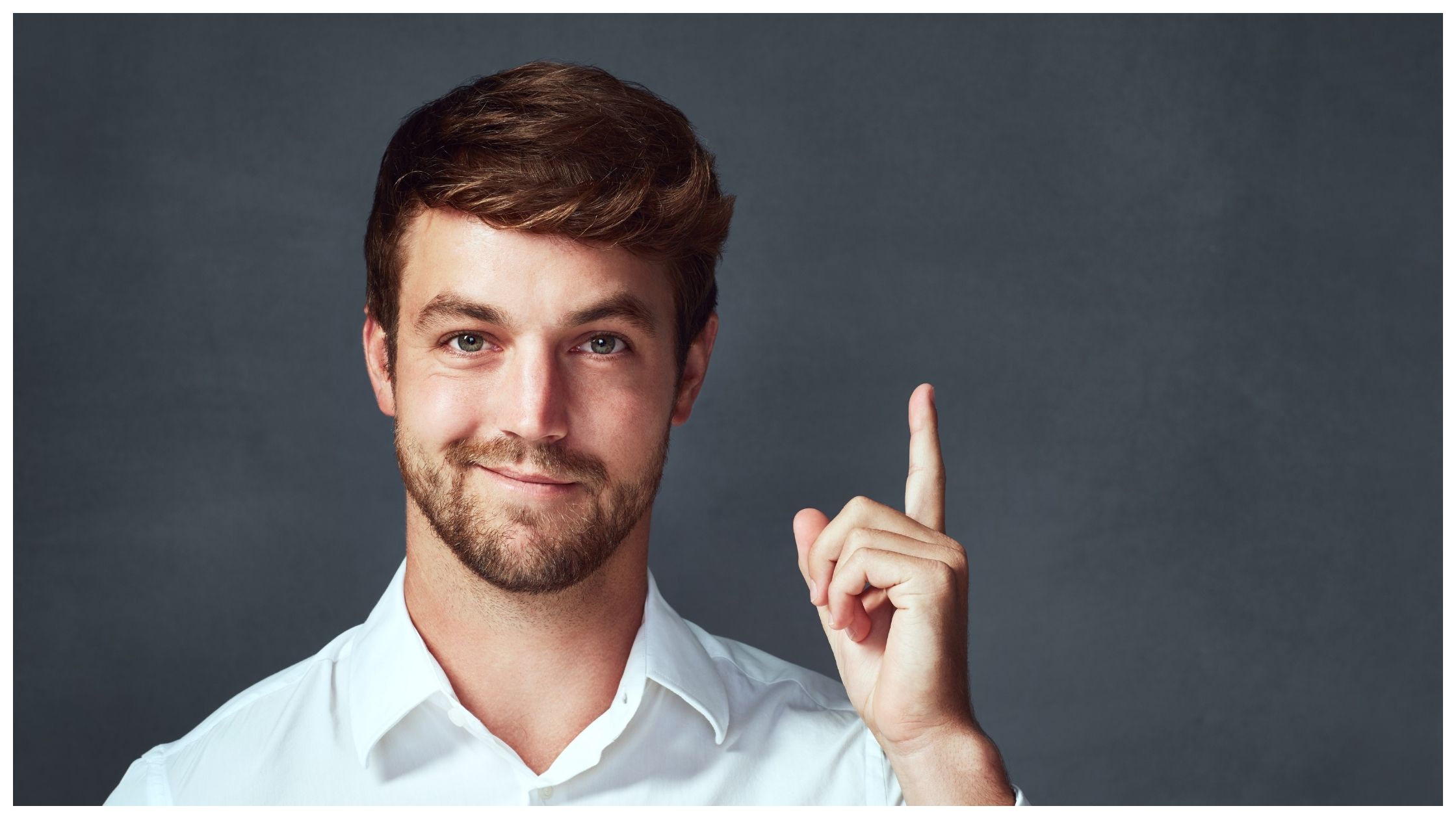 Studio portrait of a man pointing to copyspace against a dark background